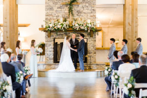 This is the wedding ceremony in front of the mantle filled with flowers at the upstairs Carriage House at Park Crest Events in Hoover, Alabama taken by Alabama Weddings.