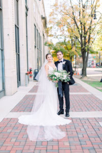 This is the bride and groom posing outside on the sidewalk in downtown Birmingham, Alabama taken by Elizabeth Bacon Photographer at the Elyton Hotel in Birmingham