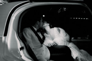 This is the bride and groom kissing in the Coats Cars getaway car at the end of the wedding reception taken by Elizabeth Bacon Photographer at St. Paul's Cathedral in Birmingham, Alabama.