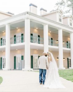 The bride and groom are kissing in front of Oak Island Masion in Wilsonville, Alabama on their wedding day taken by Leigh Grace Photography.