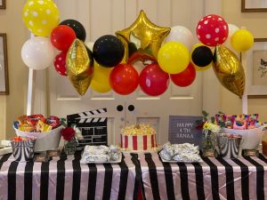 Movie themed children's party food table with popcorn themed cake, themed sugar cookies and snacks.