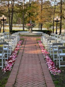 This is a fall lake wedding ceremony centered around a fountain adorned with flowers at Oak Island Mansion in Wilsonville, Alabama.